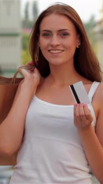Stylish Girl Joyfully Holding Shopping Bags and a Credit Card