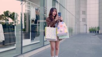 Young Happy Woman Shopper with Many Colorful Shopping Bags Stands Outside Mall...